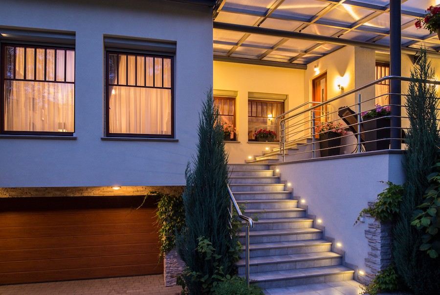 Exterior of home illuminated with stairway lighting and entry lights.